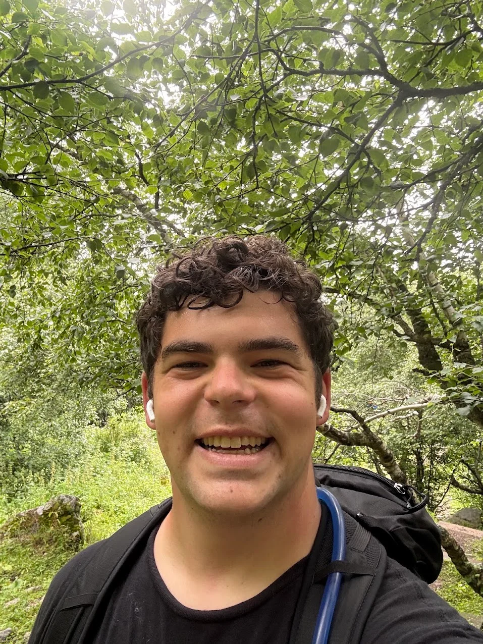 Griffin Clark smiling beneath a canopy of trees while hiking
